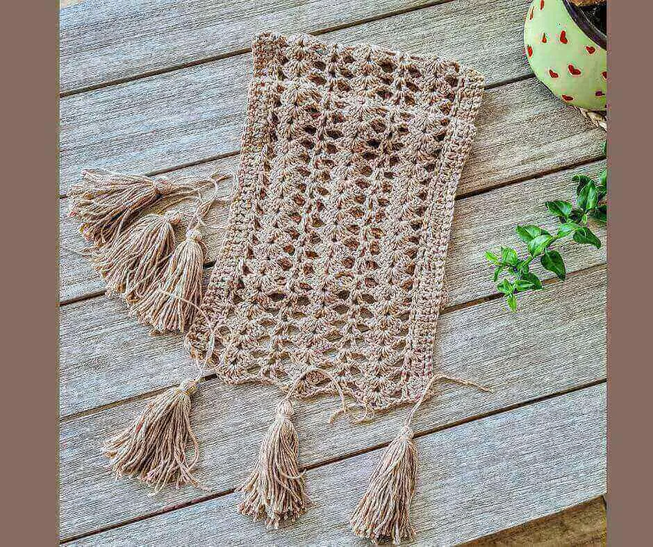 Cream beige boho crochet table runner with tassels on a wooden dining table