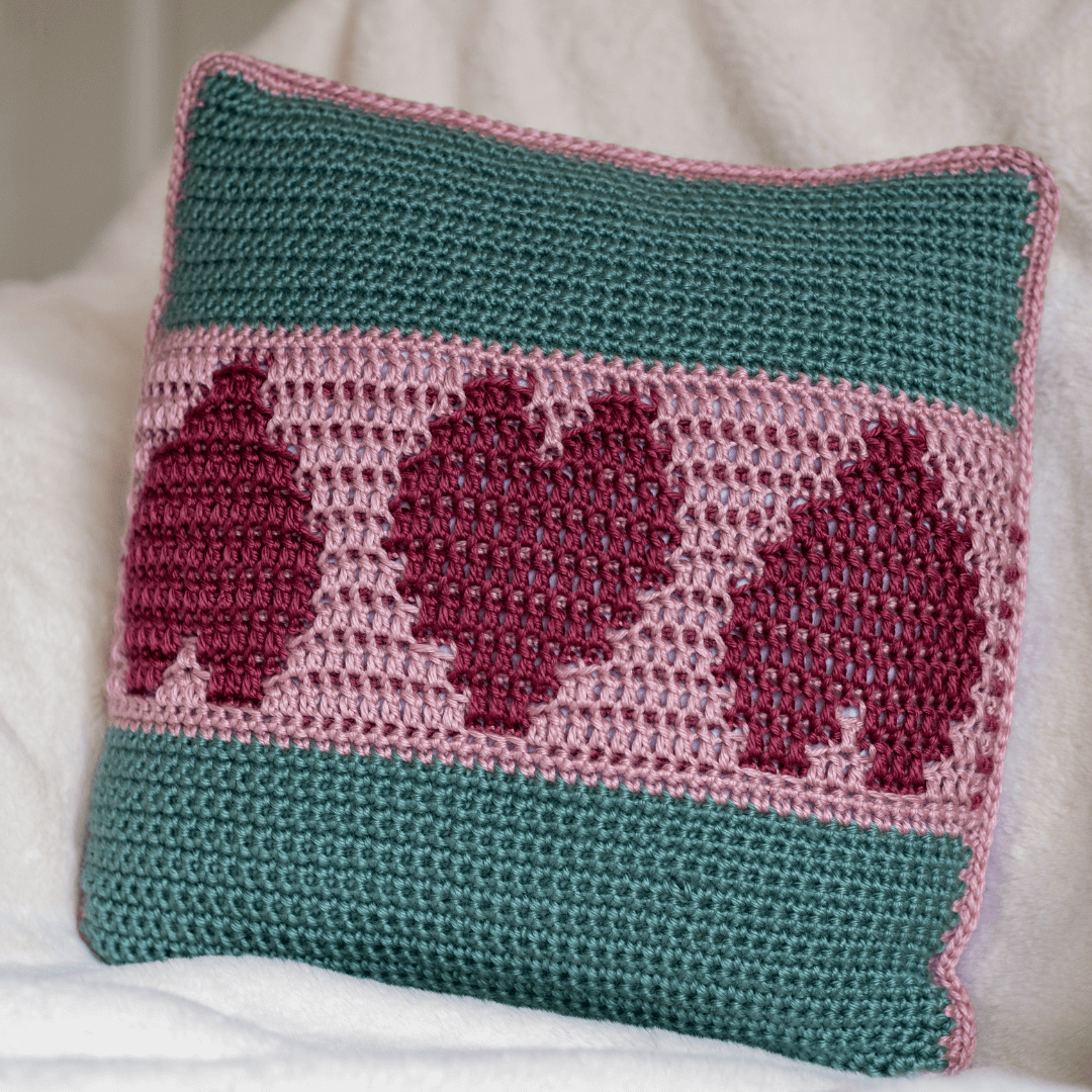 simply+love+mosaic+crocheted+cushion+cover+in+pink+and+green+sitting+on+a+cream+blanket+tiny