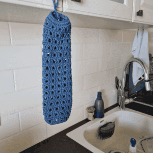 Crochet plastic bag holder in cotton hanging by the sink