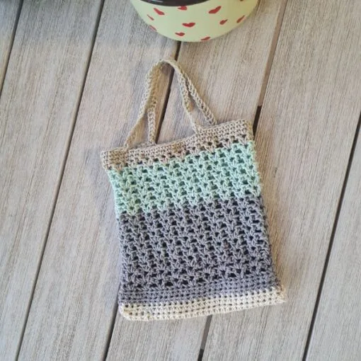 Finished crochet mesh market bag stretched to hold fresh produce showing the open V stitch weave
