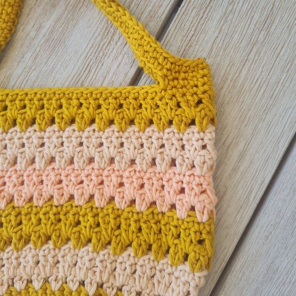 Close-up of a striped crochet tote bag with sturdy handles, made using an easy free crochet tote bag pattern.