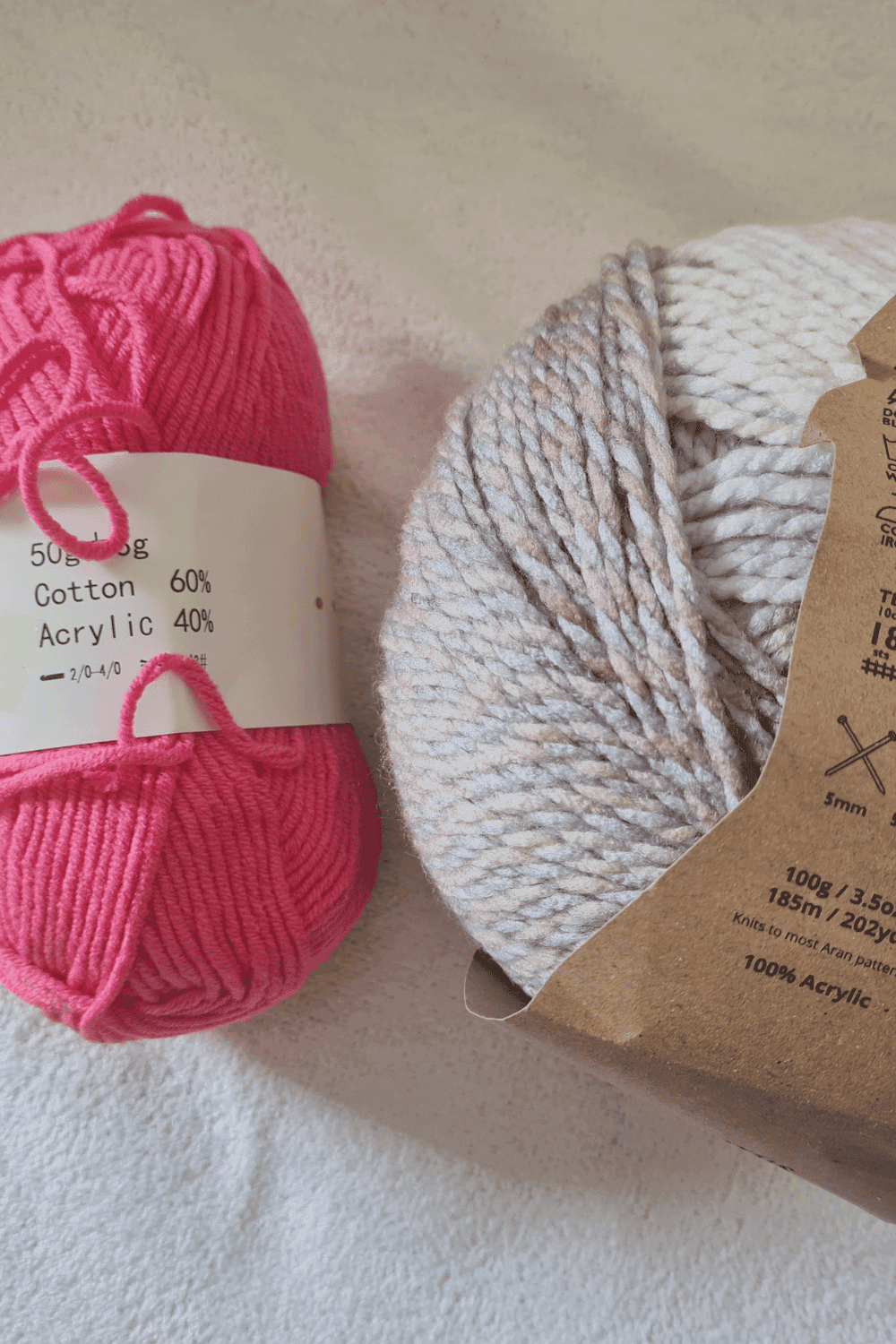 Colorful pink and neutral beige yarn balls for knitting and crochet projects.
