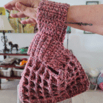 Crochet waffle stitch Japanese knot wrist bag in dusty rose variegated yarn held on wrist showing texture and handle shape