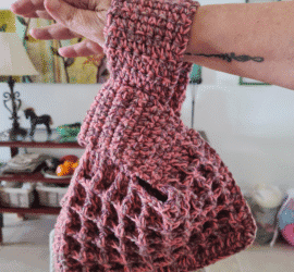 Crochet waffle stitch Japanese knot wrist bag in dusty rose variegated yarn held on wrist showing texture and handle shape