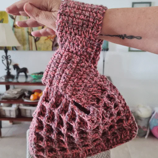 Crochet waffle stitch Japanese knot wrist bag in dusty rose variegated yarn held on wrist showing texture and handle shape