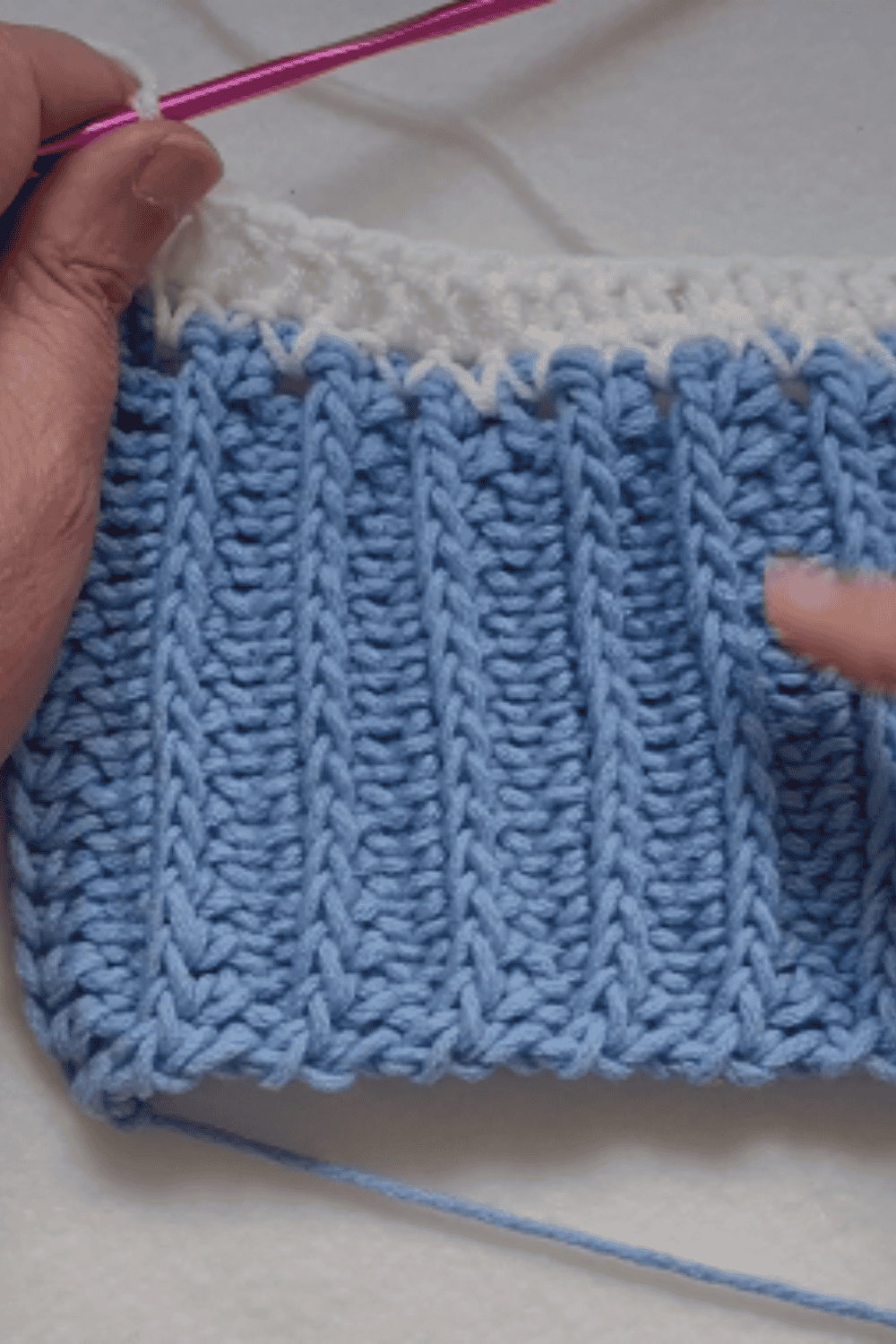 Close-up of blue and white knitted fabric with textured pattern.