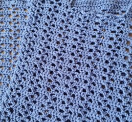 Two identical crochet rectangle panels in blue laid flat before seaming