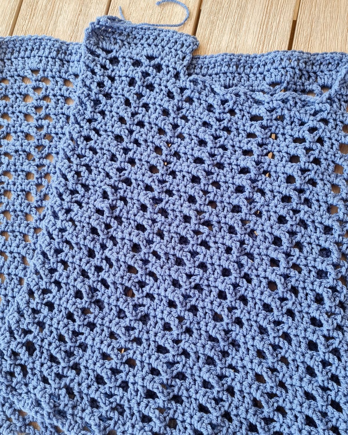 Two identical crochet rectangle panels in blue laid flat before seaming