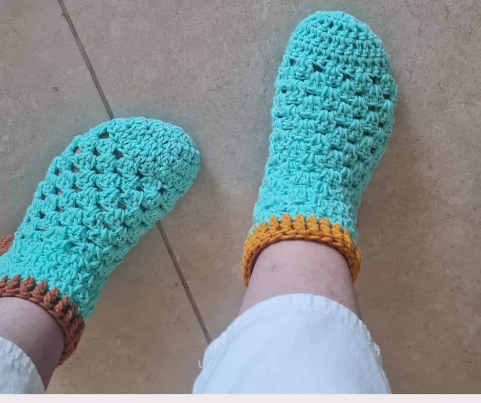 A finished pair of green and gold crochet granny slippers held up together