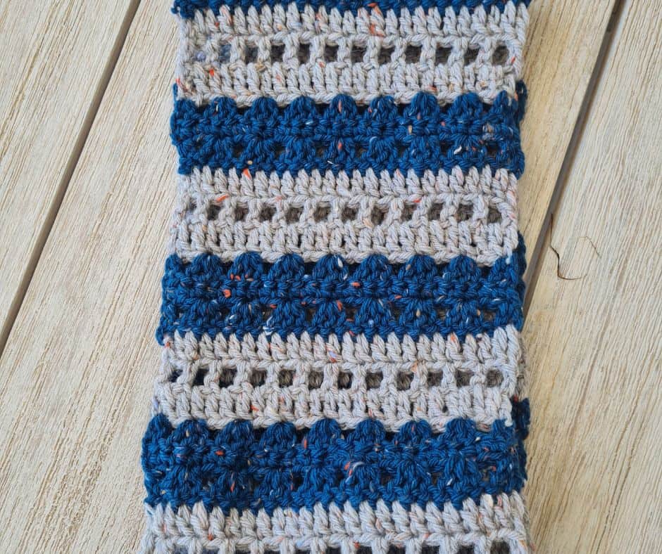 A flat panel of the striped crochet cowl showing the alternating bands of mesh, shells, and single crochet in teal and grey