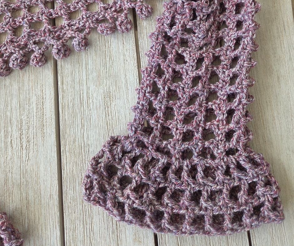 Close up of the flared bell sleeve cuff on a crochet mesh shrug worked in bulky cream yarn