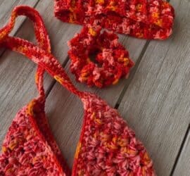Three finished summer crochet projects in pink, orange, and peach variegated yarn, an envelope bag, a coral scrunchie, and an open headband, arranged as a matching set Bag