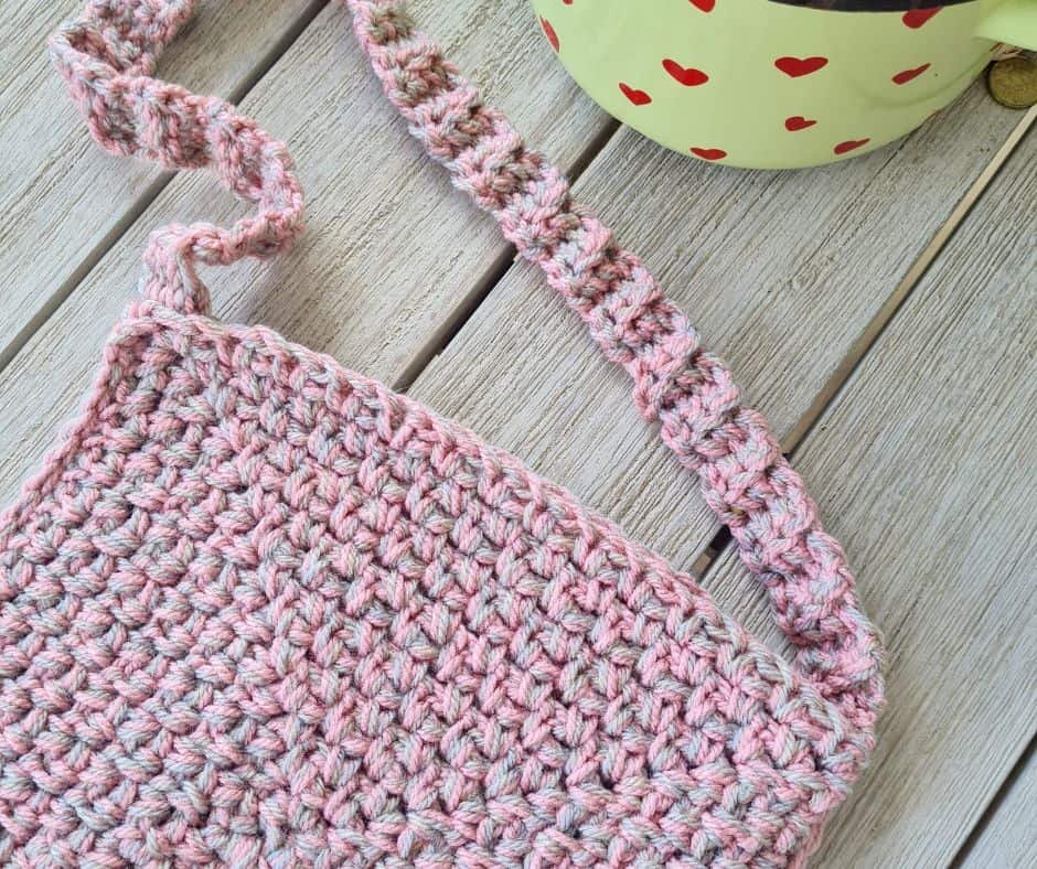 Finished pink and beige crochet bag laid flat, showing full strap and body