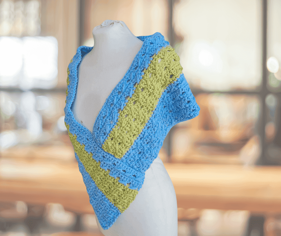Two-tone blue and olive crochet poncho wrap draped on a mannequin